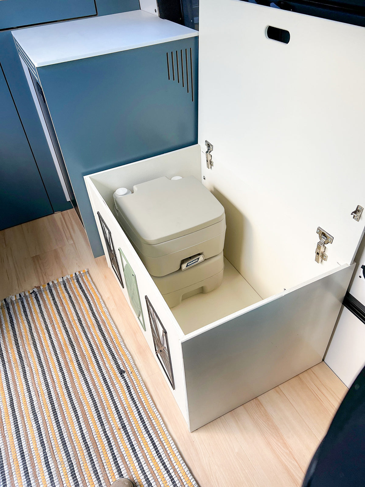 Bench seat lid open, showing storage space and a portable toilet