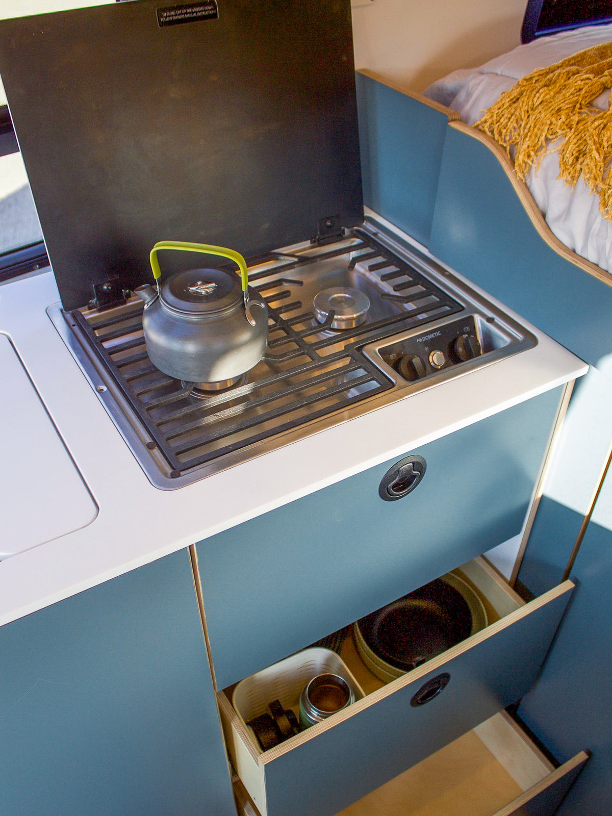 Two-burner propane stove with a kettle in the Mars galley, drawer open below