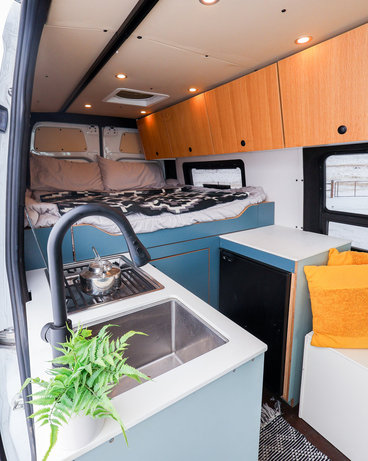 Stainless sink with a black pull-down faucet in the Mars galley, bed in the background
