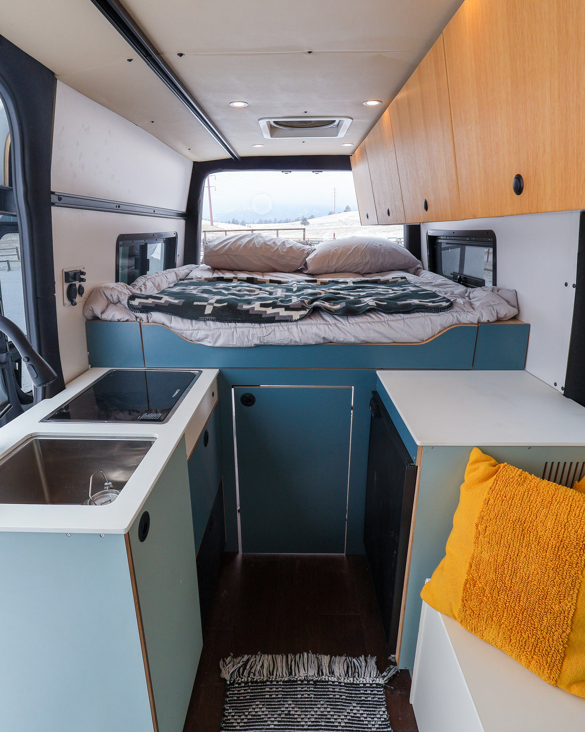 Mars interior looking toward the rear bed, with blue galley cabinets and wood upper cabinets